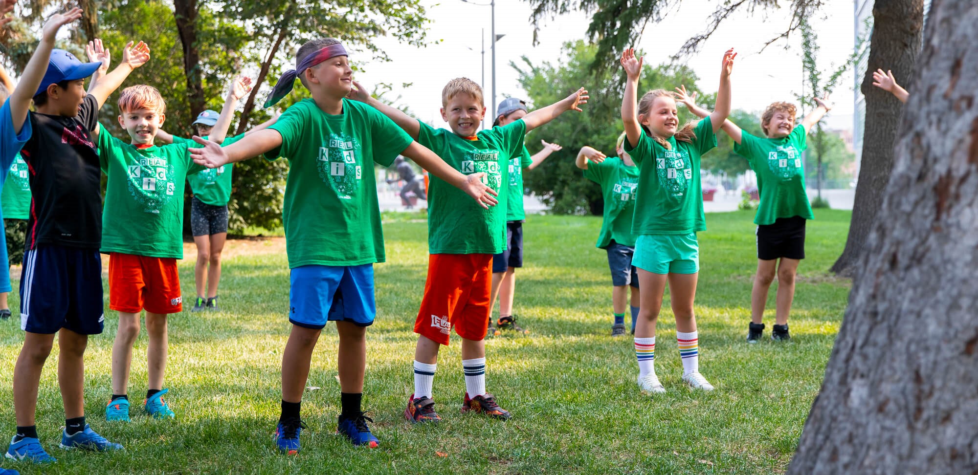 Kids exercising outdoors in green shirts.