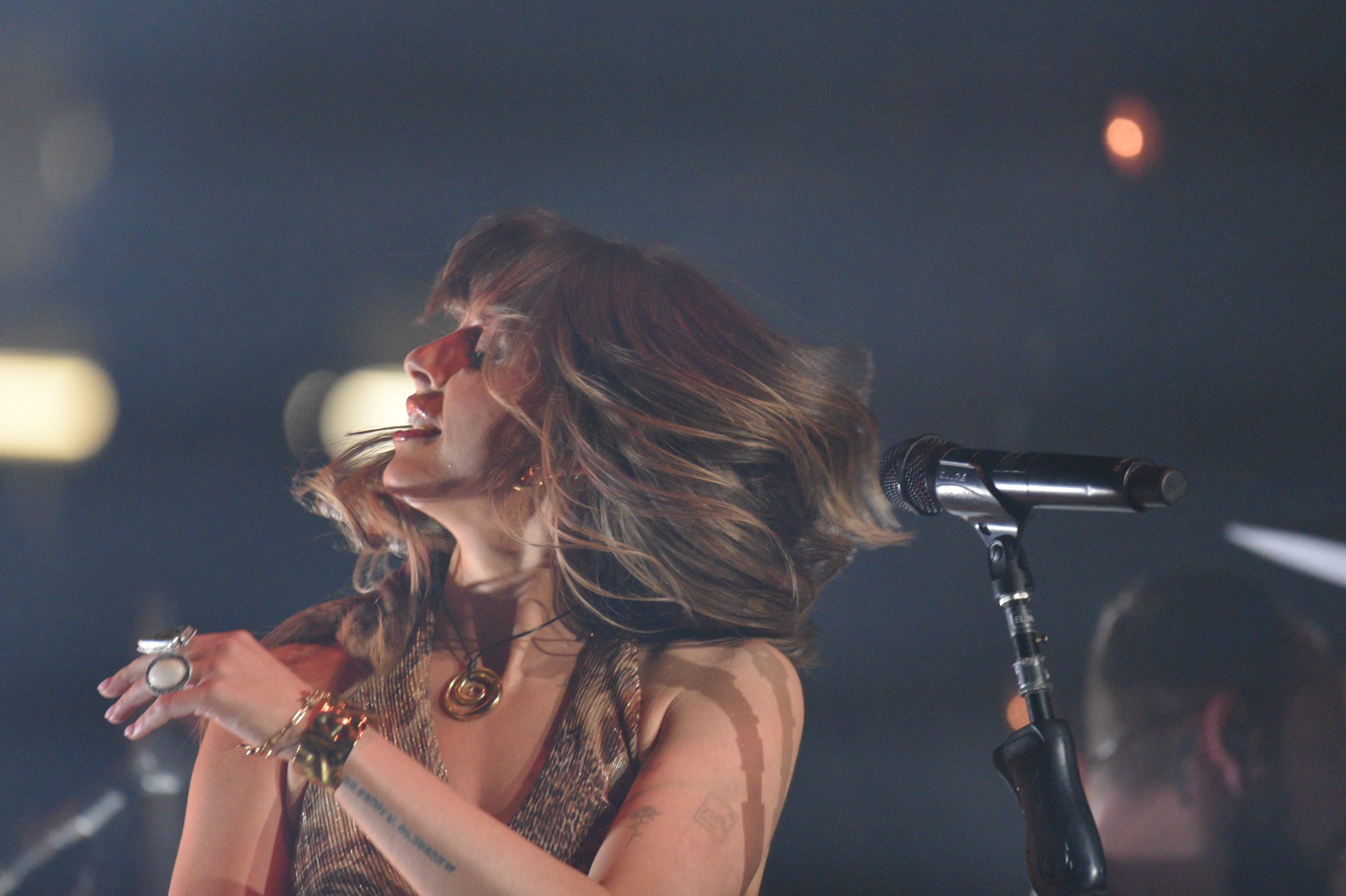 Singer performing energetically on stage with microphone.