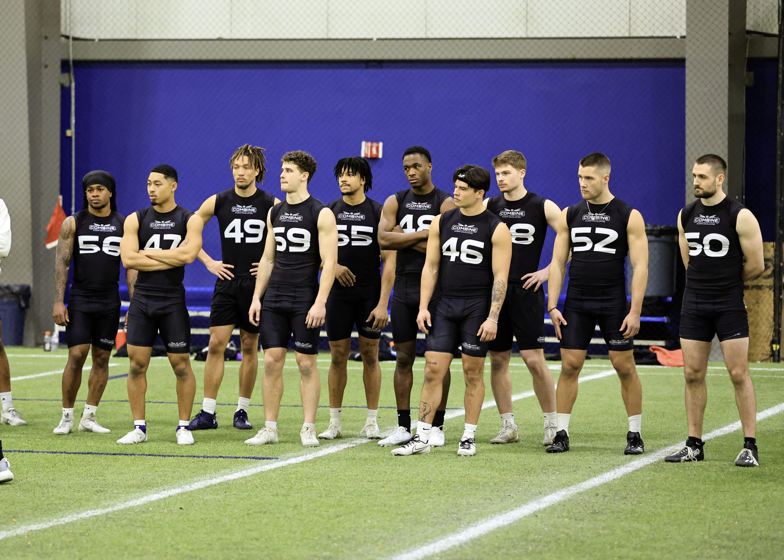 Athletes in sports uniforms standing indoors.