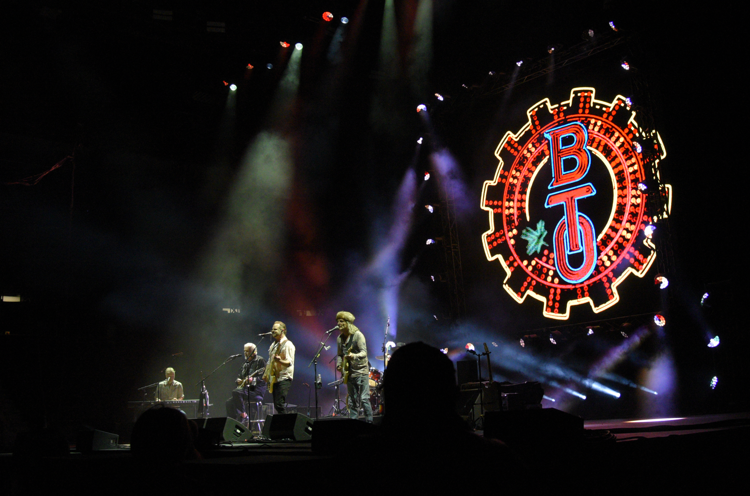 Band performing on stage with illuminated BTU sign.