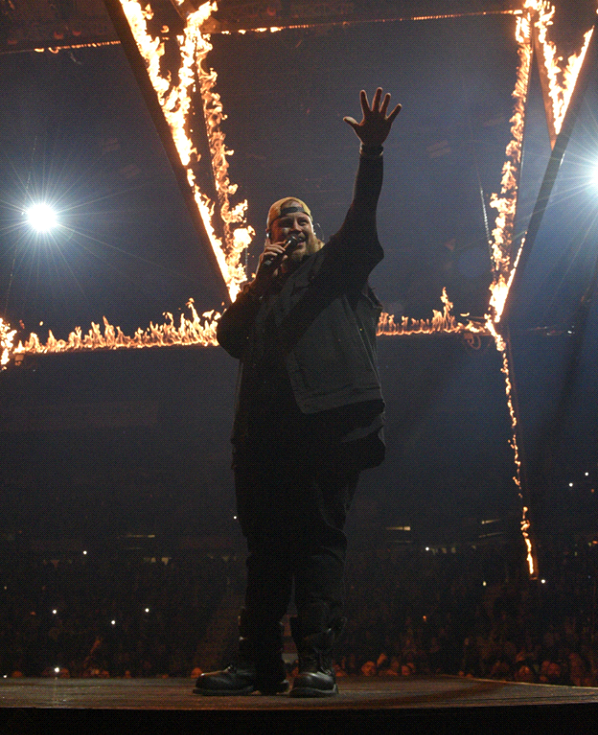 Performer on stage with fiery lighting effects.