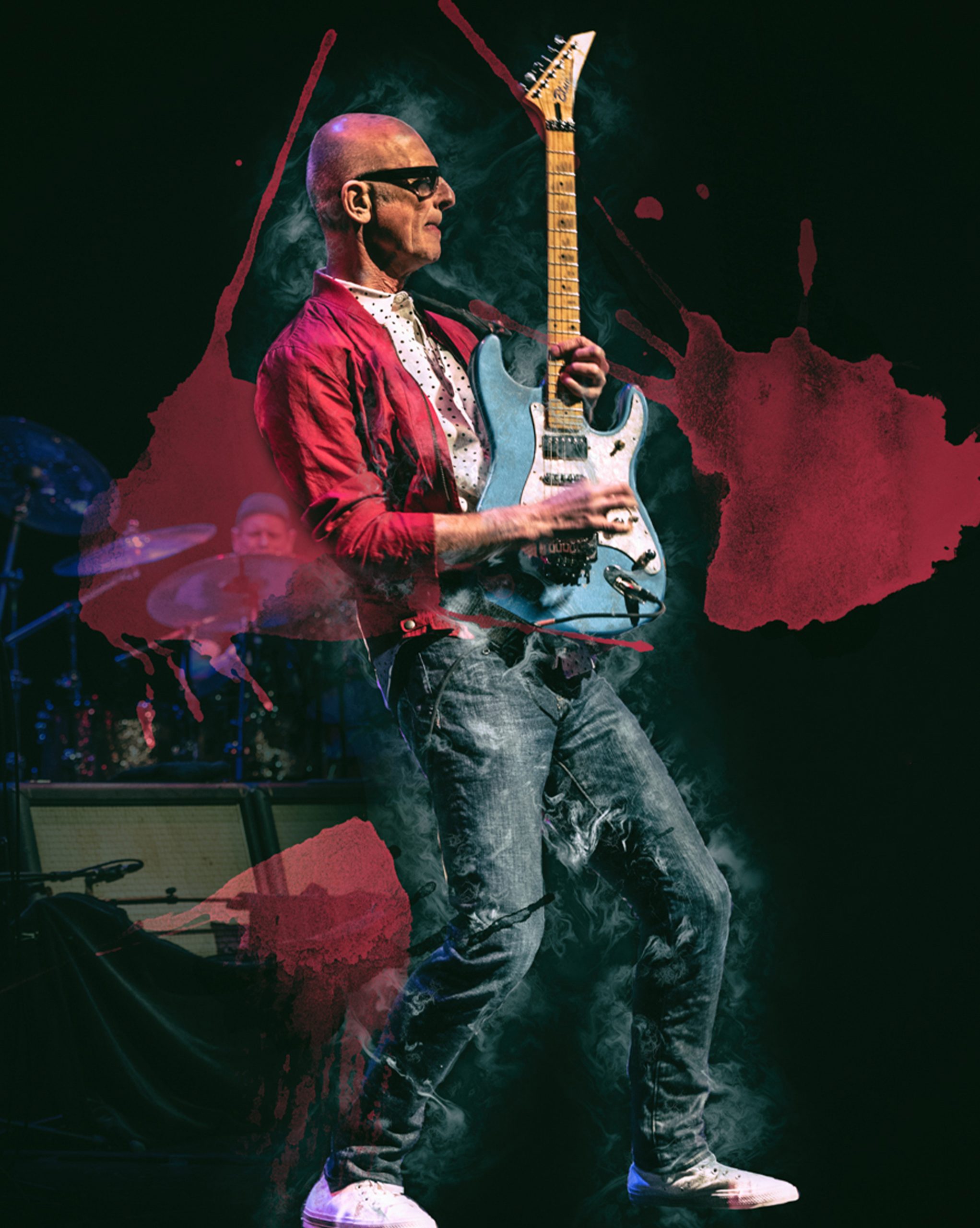 Musician playing electric guitar on stage with effects.