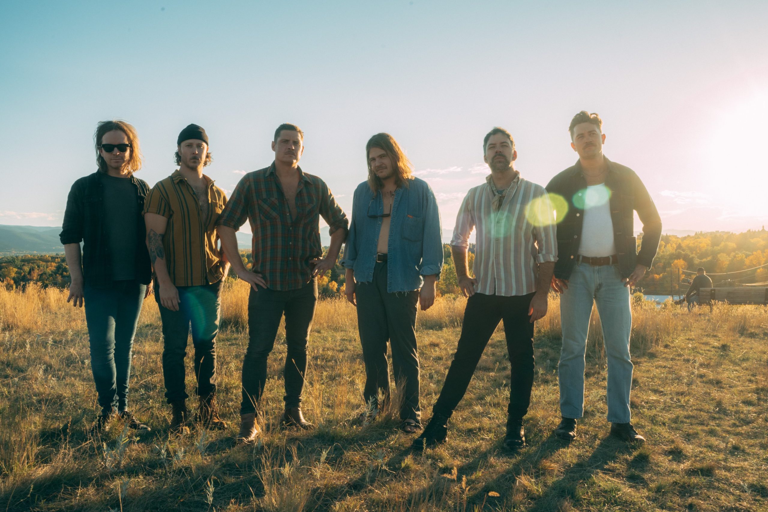 Six people stand in a sunny field.