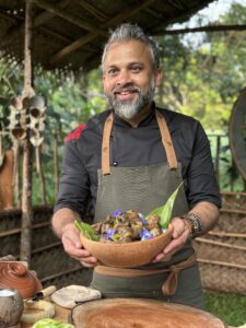 Chef holding a bowl of prepared food outdoors.
